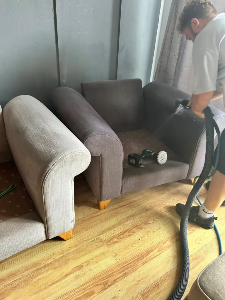 grime bustered employee workin to clean a sofa